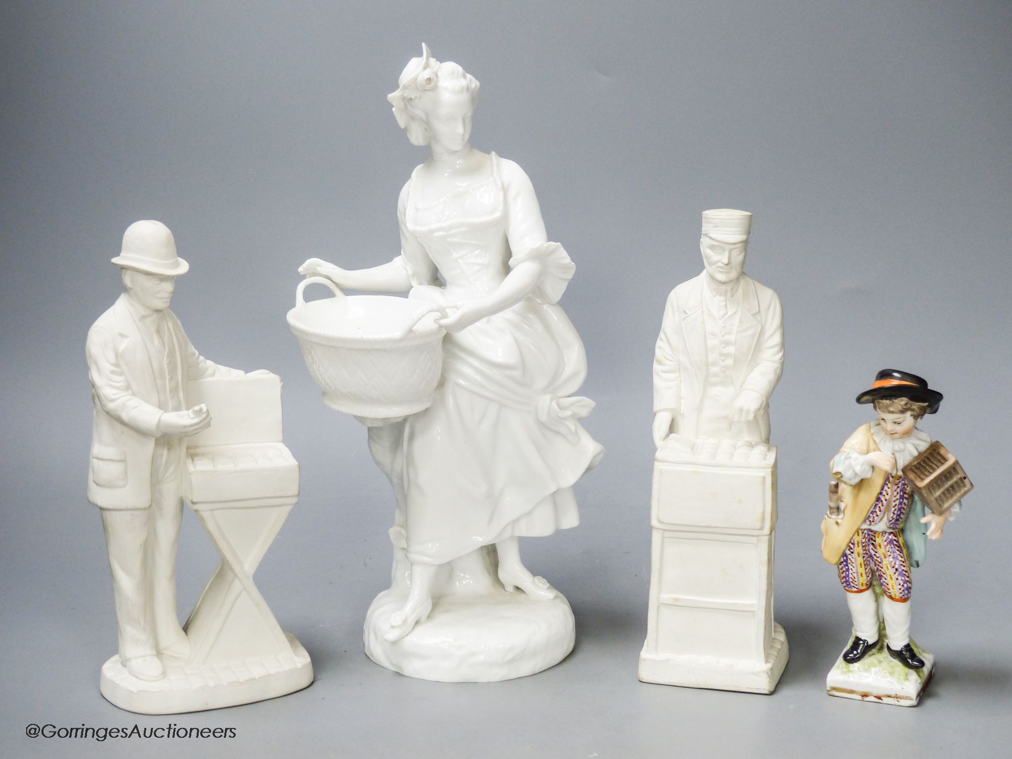 A French white glazed figure, a pair of biscuit porcelain figures of street sellers and a Berlin figure, tallest 27cm
